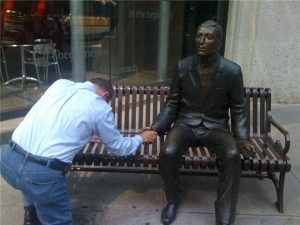 Man praying with a statue and holding it's hand